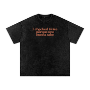 Black acid-washed oversized T-shirt with coral “I checked twice porque uno nunca sabe” text.