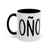 White accent coffee mug with black interior and handle featuring “Coño” in black lettering on a white background.