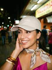 Woman wearing a beige embroidered dad cap reading “improvisando” during a nighttime outing.