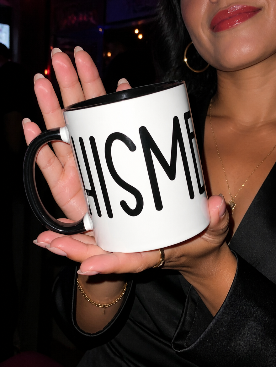 Close-up lifestyle photo of a white and black “Chisme” mug during a nighttime outing.