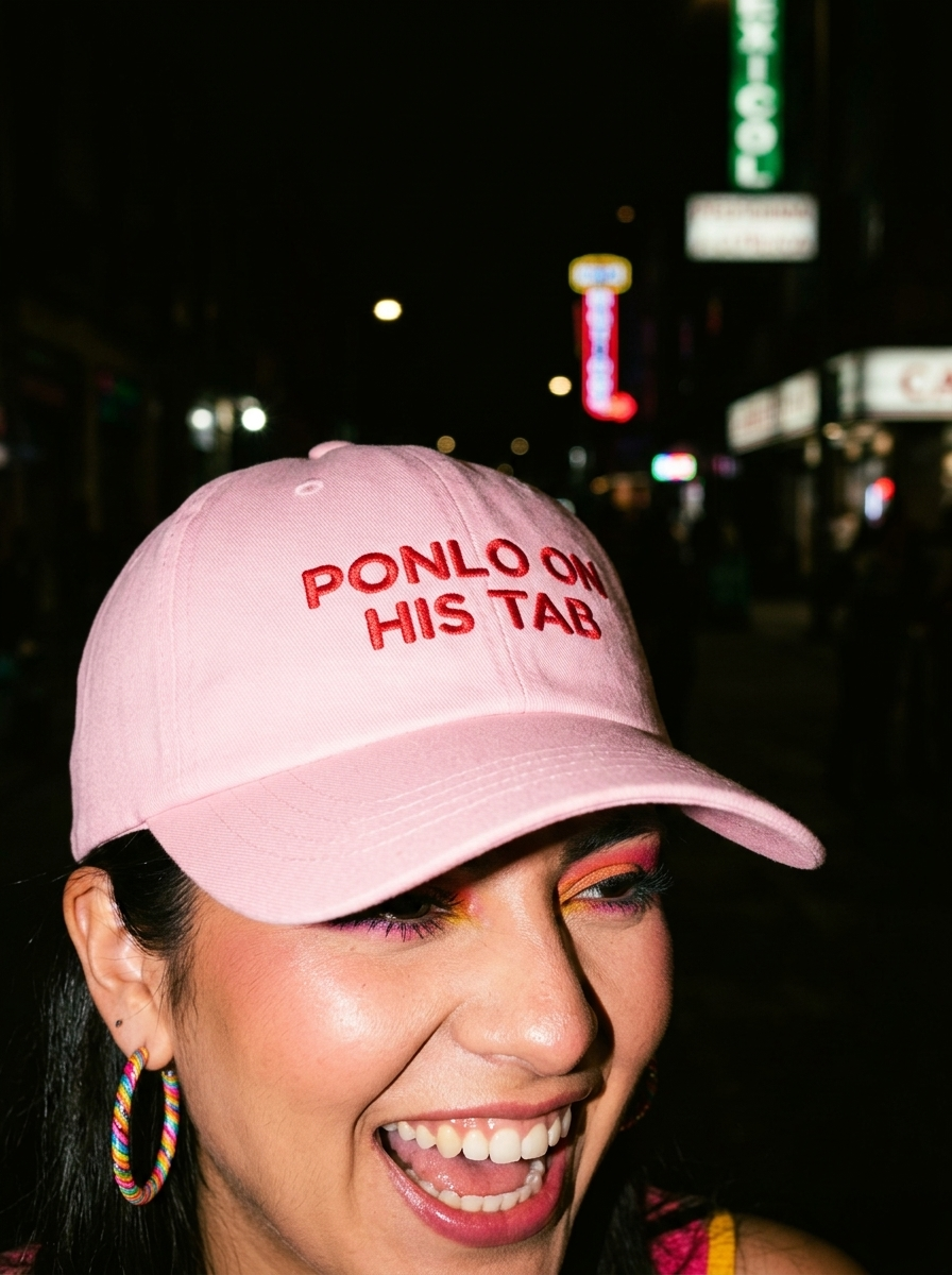 Woman wearing a pink embroidered dad cap reading “Ponlo on his tab” during a nighttime outing.
